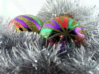 Two multi-coloured christmas spheres in a tinsel