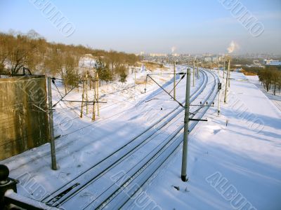 Railroad tracks covered by a snow near a hill