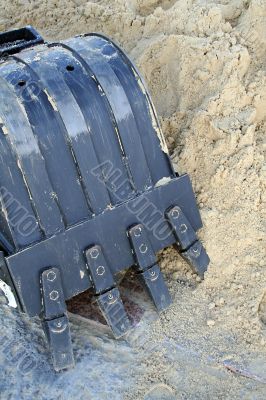 Black shovel bucket near to a heap of sand