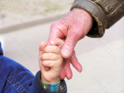 The kid holds a hand of the grandfather
