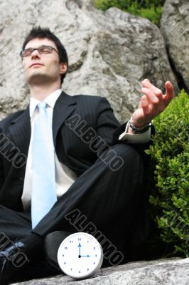 Businessman meditating outside.
