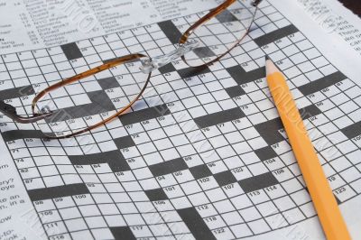 reading glasses and a pencil on a crossword puzzle