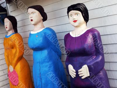 Three female statues in bright clothing