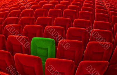 One green chair among many red seatings