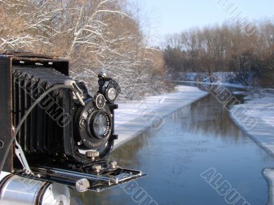Ancient photo camera shoting snowy riverside