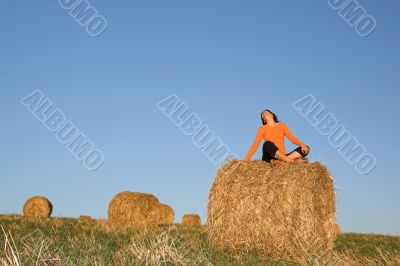 Beautiful woman seated in hay bale