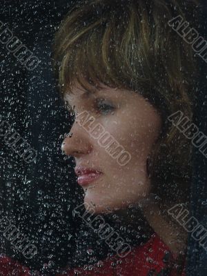 Girl looks thru waterdropped widow glass