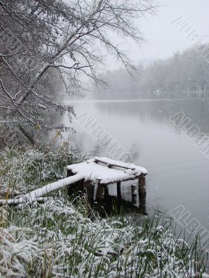 First season snowfall on riverside water