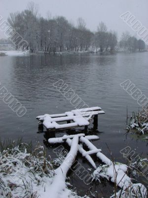 First season snowfall on riverside water