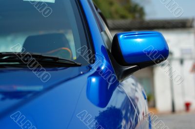 Right side mirror of shiny blue car