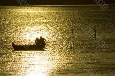 Two fisherman in water with back light