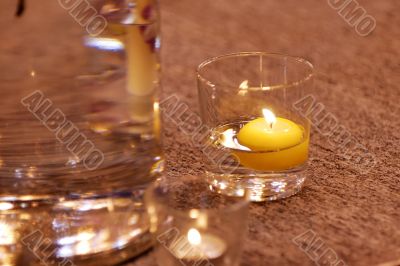 Burning candle in water glass