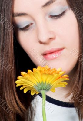 beautiful girl smelling yellow daisy
