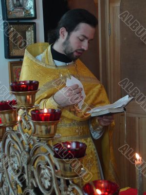 orthodox priest praying with Gospel in hands