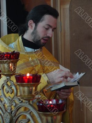 orthodox priest praying with Gospel in hands