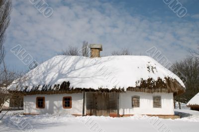 Peasant`s house under snow