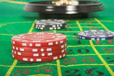 casino tokens and roulette - focus on red tokens