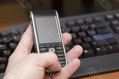 cellular phone in hand of a man on a workplace