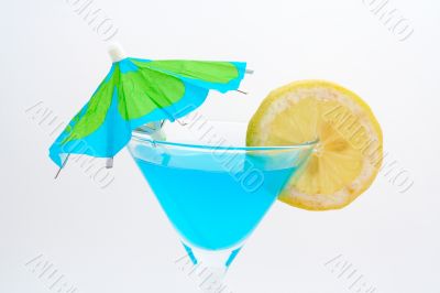 Detail of blue cocktail with lemon and umbrella