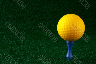 Yellow golfball and blue tee