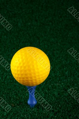 Yellow golfball and blue tee