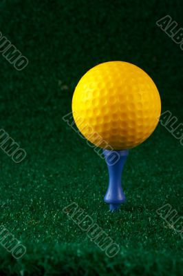 Yellow golfball and blue tee