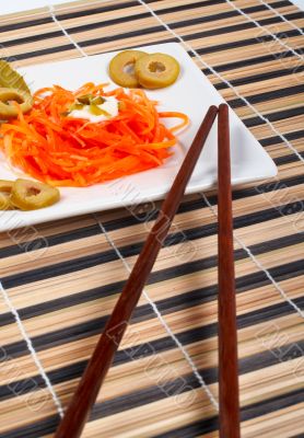 Salad of carrot on a porcelain plate with sticks Salad of carrot on a porcelain plate with sticks