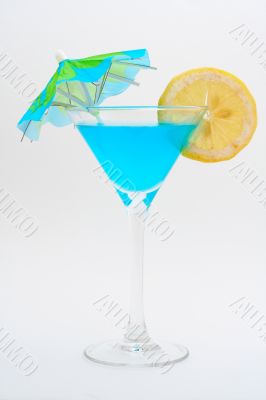 Detail of blue cocktail with lemon and umbrella