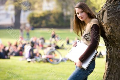leaning against a tree with notebook