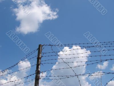 Cloudy blue sky with rugged wire fence