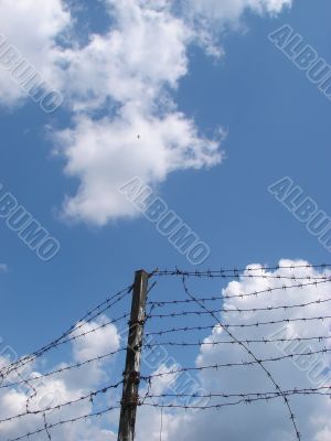 Cloudy blue sky with rugged wire fence