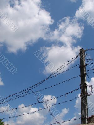 Cloudy blue sky with rugged wire fence