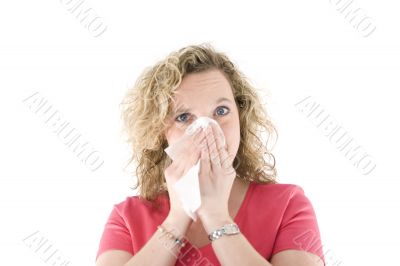 Young blond girl sneezing in the handkerchief