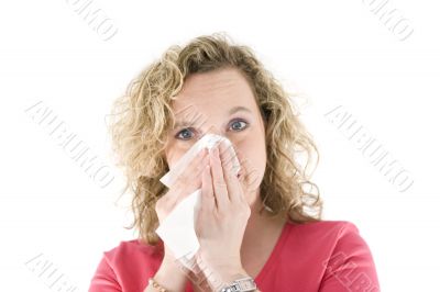 Young blond girl sneezing in the handkerchief