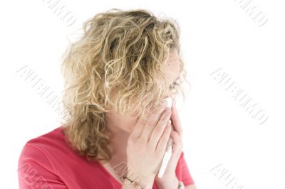 Young blond girl sneezing in the handkerchief