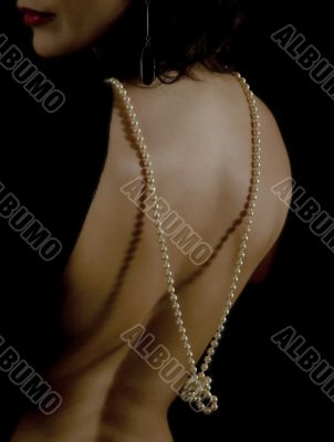 Clous-up of a woman`s back having a low neckline with pearl necklace