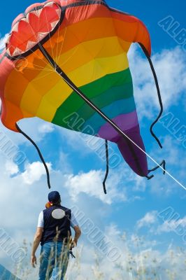 man plays with big colorful fish kite