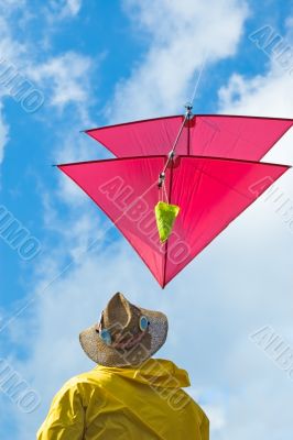 man plays with red kite in sunny summer day