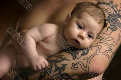 The baby on man`s hands with a tattoo