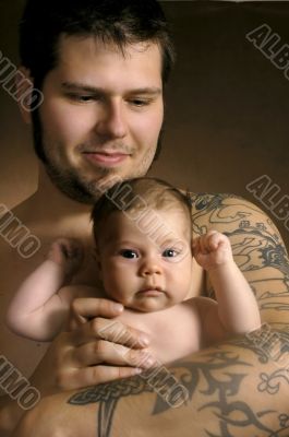 The baby on hands at the man with a tattoo
