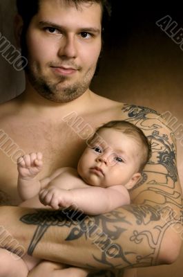 The baby on hands at the man with a tattoo