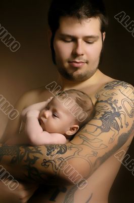 The baby on hands at the man with a tattoo