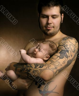 The baby on hands at the man with a tattoo