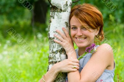 Smiling girl embrace a birch tree