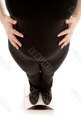 pregnant lady weighing oneself, focus on belly