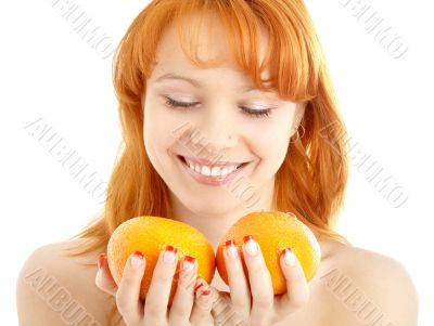 cheerful redhead holding two oranges over white