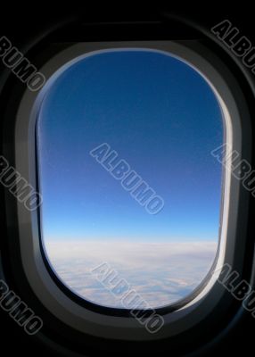 View from aeroplane window onto cloud &amp; blue sky.
