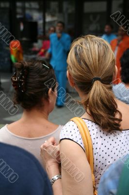 Two young women watching samba band