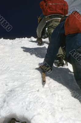 Climbers kicking steps up steep snow