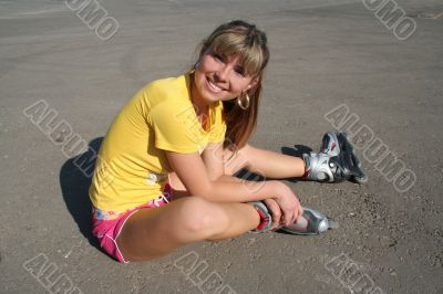 Girl sits on the floor with roller blades